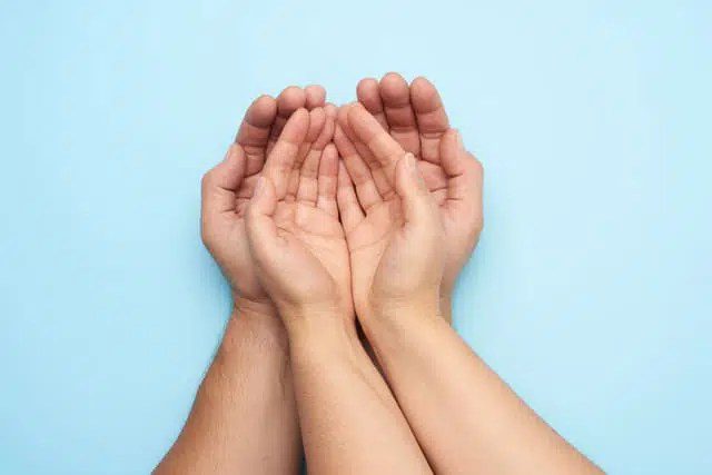 Two Female Hands Lie in Male Palms On a Blue Background